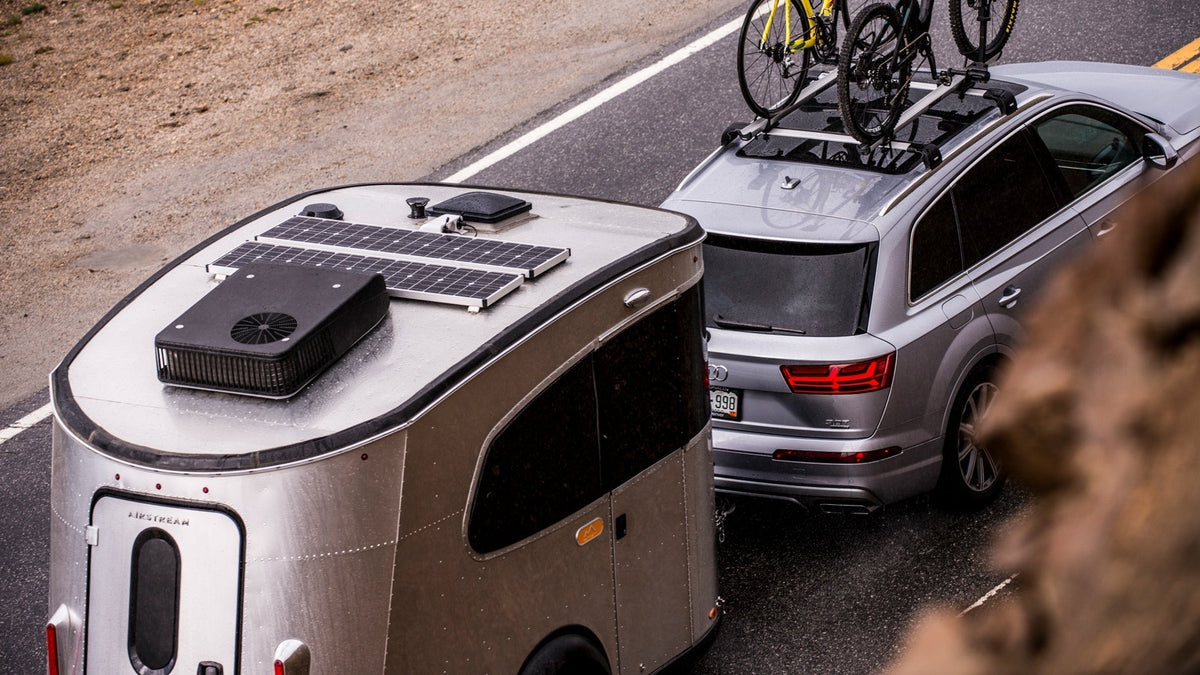Airstream Basecamp trailer with a Zamp Solar panel on the roof, towed by an SUV