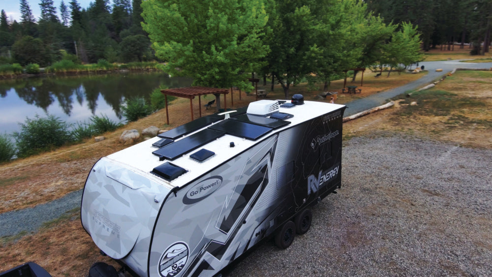 Travel trailer with rooftop solar parked by a lake