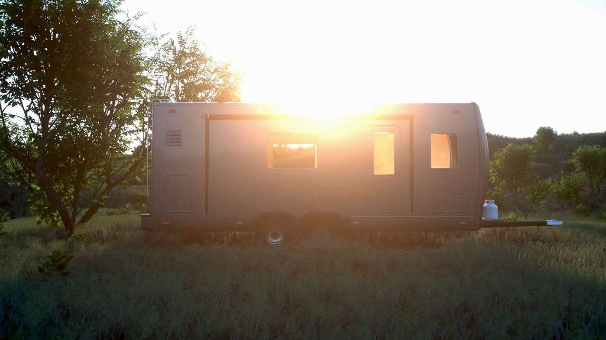 Travel trailer parked in a meadow at sunset
